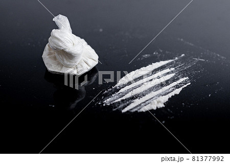 white powder (heroin, cocaine, narcotic) in a plastic bag on a black background, drugs are scattered in the form of a track 81377992