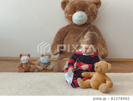 Child playing with his sick teddy bears wearing medical mask against viruses. Role playing, child playing doctor with plush toy. Children and illness concept. 81378402
