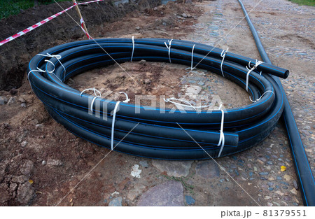 A circle of black plastic pipe lies on the ground. The concept of communications 81379551