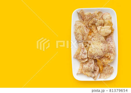 Crispy taro chips in white plate on yellow background. 81379654