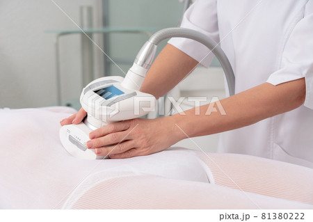 Woman in special white suit getting anti cellulite massage in a spa salon. LPG, and body contouring treatment in clinic. Woman in special white suit getting anti cellulite massage in a spa salon. LPG, and body contouring treatment in clinic. 81380222