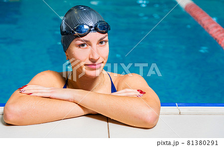 Portrait of Young smiling woman swimmer wearing goggles in indoor swimming pool 81380291