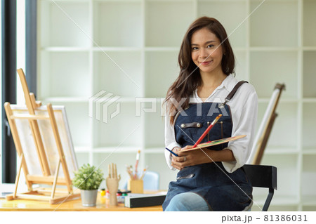 Elegant asian artist woman sitting and holding colour palette and paintbrush 81386031