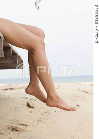 Woman's legs sitting and relax at beach jetty in summer Woman's legs sitting and relax at beach jetty in summer 81386553