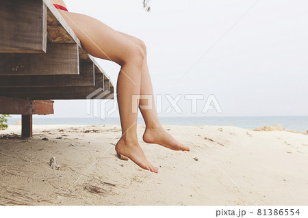 Woman's legs sitting and relax at beach jetty in summer Woman's legs sitting and relax at beach jetty in summer 81386554