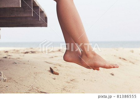 Woman's legs sitting and relax at beach jetty in summer 81386555