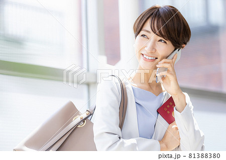 パスポート持ってスマホで通話している女性 パスポート持ってスマホで通話している女性 81388380