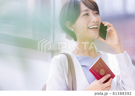 パスポート持ってスマホで通話している女性 パスポート持ってスマホで通話している女性 81388392