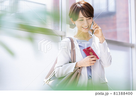 パスポート持ってスマホで通話している女性 81388400