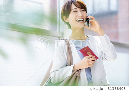 パスポート持ってスマホで通話している女性 パスポート持ってスマホで通話している女性 81388403