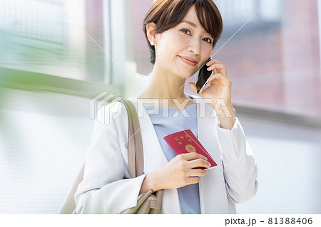 パスポート持ってスマホで通話している女性 パスポート持ってスマホで通話している女性 81388406