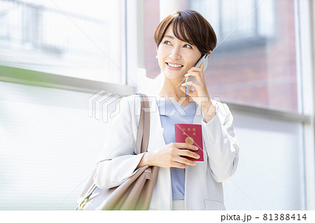 パスポート持ってスマホで通話している女性 パスポート持ってスマホで通話している女性 81388414