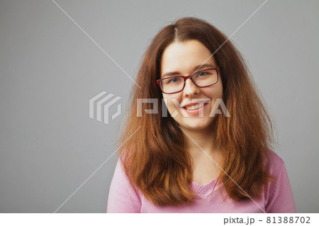 Girl with glasses smiles. Young redhead woman portrait on a solid white background 81388702