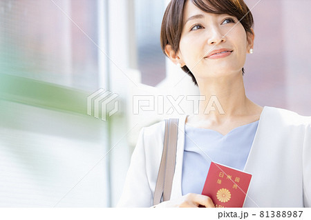パスポートを持って明るい窓辺に立っている女性 パスポートを持って明るい窓辺に立っている女性 81388987