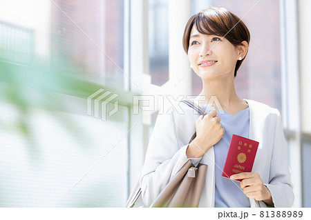 パスポートを持って明るい窓辺に立っている女性 81388989