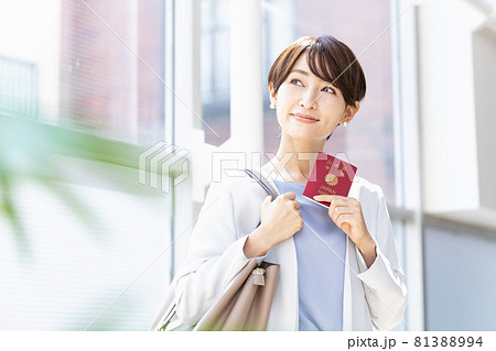 パスポートを持って明るい窓辺に立っている女性 81388994