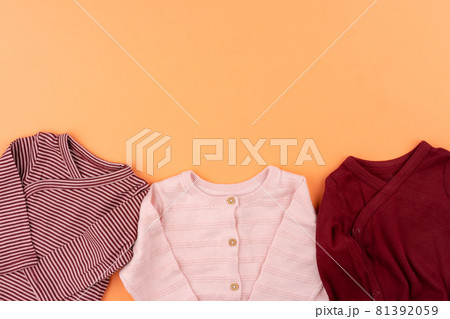 Clothes of baby girl on orange background top view Clothes of baby girl on orange background top view 81392059