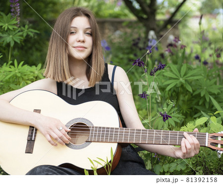 Teenager girl playing guitar in park Teenager girl playing guitar in park 81392158