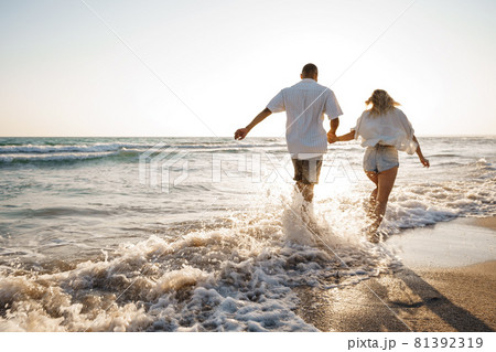Young beautiful couple walking on beach near sea Young beautiful couple walking on beach near sea 81392319