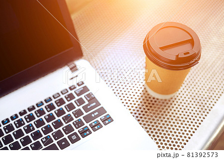 Mockup image of laptop with blank black screen and coffee cup on metal bench in nature outdoor park 81392573
