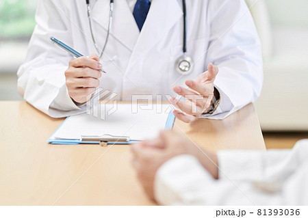 患者に症状を説明する男性医師の手元 81393036