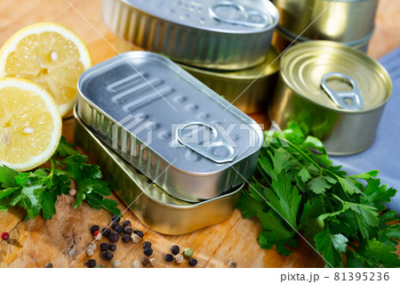 Tin cans with ring pull on wooden surface with lemon and greens Tin cans with ring pull on wooden surface with lemon and greens 81395236