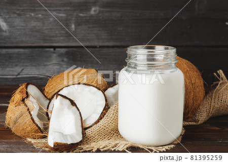 Broken coconut and coconut milk on black wooden background 81395259