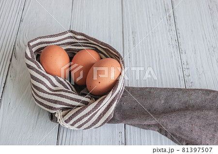 Brown chicken eggs lay on the wooden floor with brown fabric, vintage style. 81397507