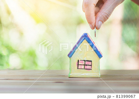House is put on a table, the hand of a coin man into the house. House is put on a table, the hand of a coin man into the house. 81399067