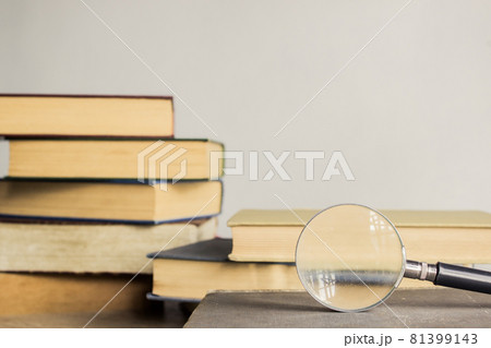 Open book and a magnifying glass over the light wall. 81399143