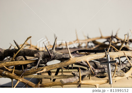 A cross with thorn crown on a wooden table.  81399152