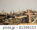 A wooden cross with thorn crown on a wooden table.  81399153