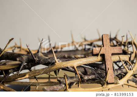 A wooden cross with thorn crown on a wooden table.  81399153