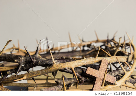 A wooden cross with thorn crown on a wooden table.  81399154