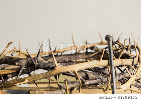 A thorn crown with nail on a wooden table.  81399155