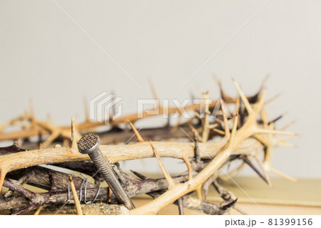 A thorn crown with nail on a wooden table.  81399156