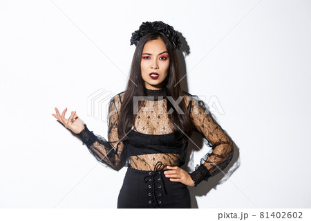 Angry and confused asian woman in witch costume looking bothered by annoying quetion, raising hand up and stare at camera pissed-off. Female at halloween party standing frustrated Angry and confused asian woman in witch costume looking bothered by annoying quetion, raising hand up and stare at camera pissed-off. Female at halloween party standing frustrated 81402602