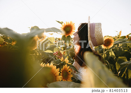 Young woman having a walk in sunflowers field in the morning 81403513