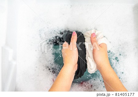 Female hands washing black and white clothes together 81405177