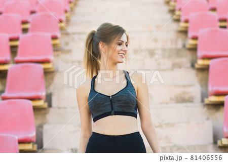 A female coach with dark hair stands on the red running track of the stadium 81406556