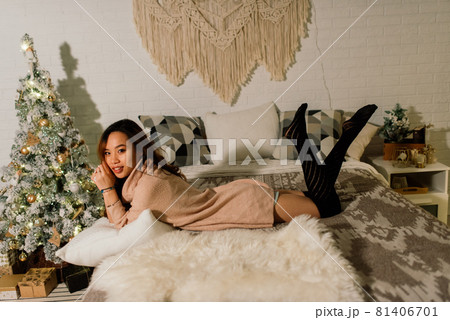Beautiful young asian woman celebrating christmas at home, having fun while opening presents 81406701