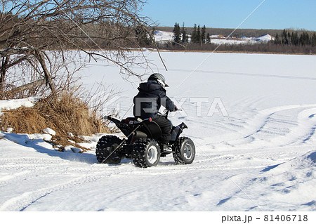 Child Driving His Quad Onto a Frozen Lake 81406718