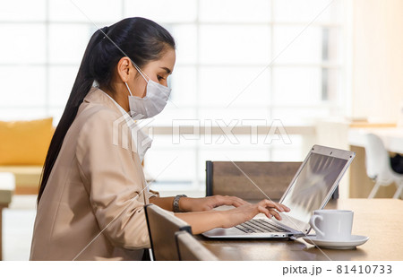 covid-19 prevention and social distancing in the company. Asian female office worker wearing a facemask and sitting alone in the office. Coronavirus protection concept covid-19 prevention and social distancing in the company. Asian female office worker wearing a facemask and sitting alone in the office. Coronavirus protection concept 81410733