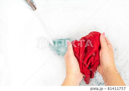Female hands washing color clothes with running water in the sink Female hands washing color clothes with running water in the sink 81411757