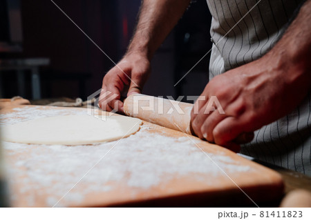 hands roll the dough into a thin layer. Cooking pizza, noodles or pitta at home hands roll the dough into a thin layer. Cooking pizza, noodles or pitta at home 81411823
