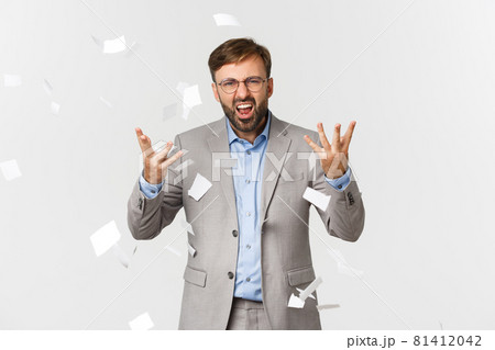 Angry businessman tearing documents and looking frustrated, tossing paper, standing mad in grey suit over white background Angry businessman tearing documents and looking frustrated, tossing paper, standing mad in grey suit over white background 81412042