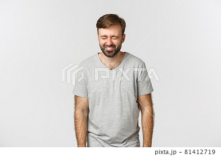 Image of cheerful bearded guy in gray t-shirt, laughing and having fun, standing over white background 81412719