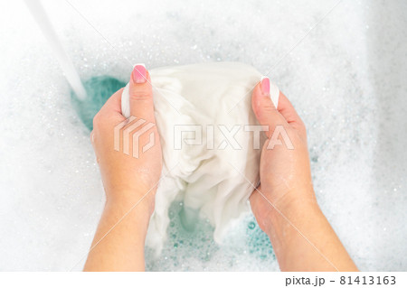 Hand washing white clothes in sink to bleach Hand washing white clothes in sink to bleach 81413163
