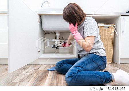 Woman sitting near leaking sink in laundry room calling for help Woman sitting near leaking sink in laundry room calling for help 81413165