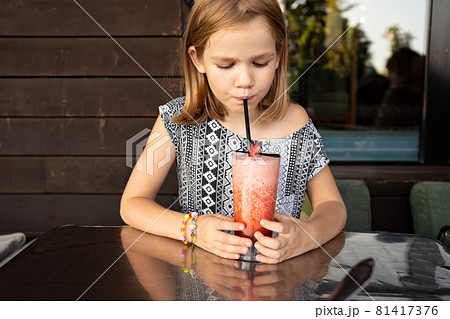 Funny little girl drinks through cocktail tube...の写真素材